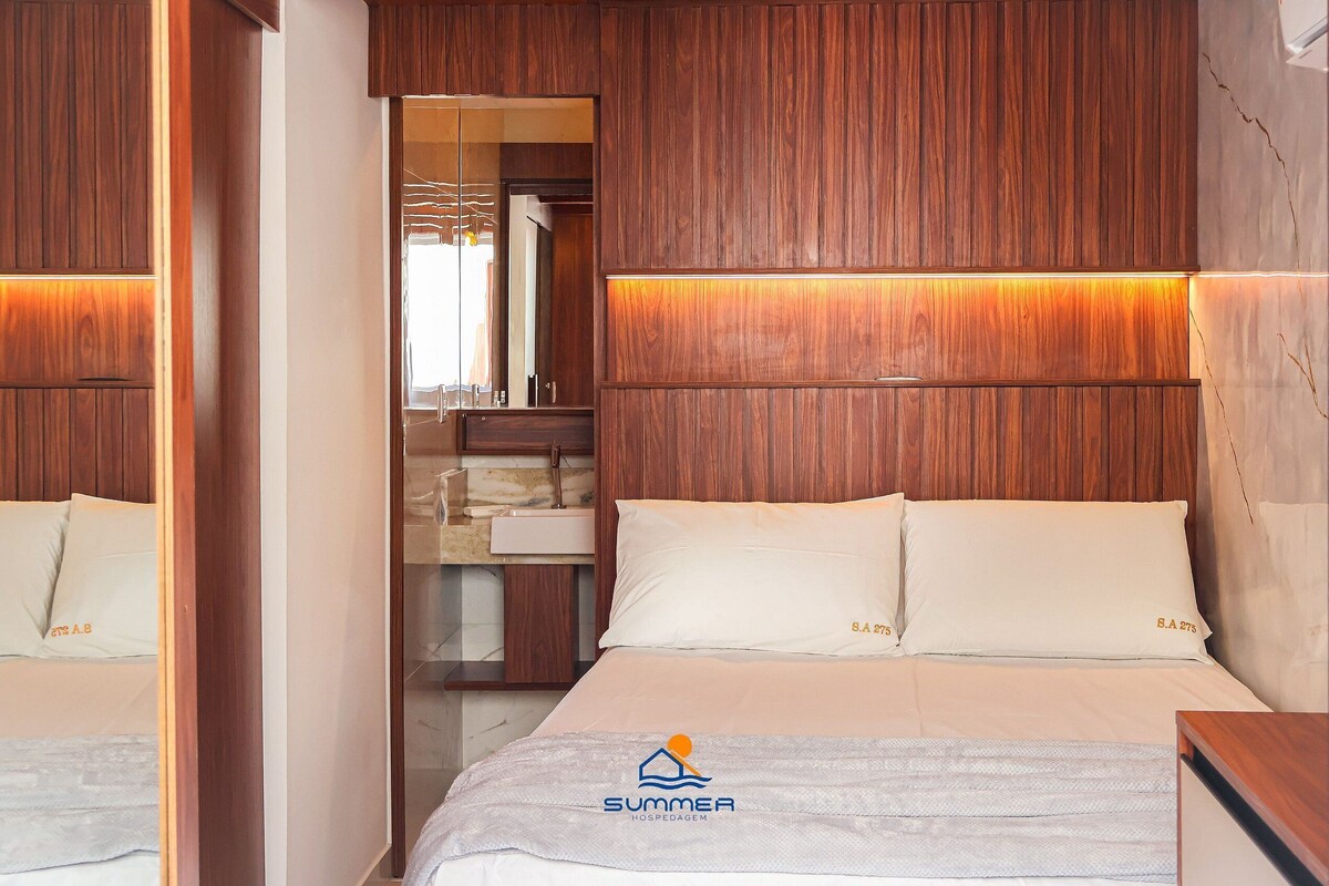 A bedroom with a wooden headboard, a bed with white bedding, and a nightstand.