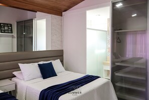 Un dormitorio con cama, mesita de noche, armario y puerta corrediza de vidrio que da al baño.