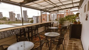 An outdoor patio area with multiple round tables and chairs, a refrigerator, and potted plants. - Toukan Hostel (Pereira)