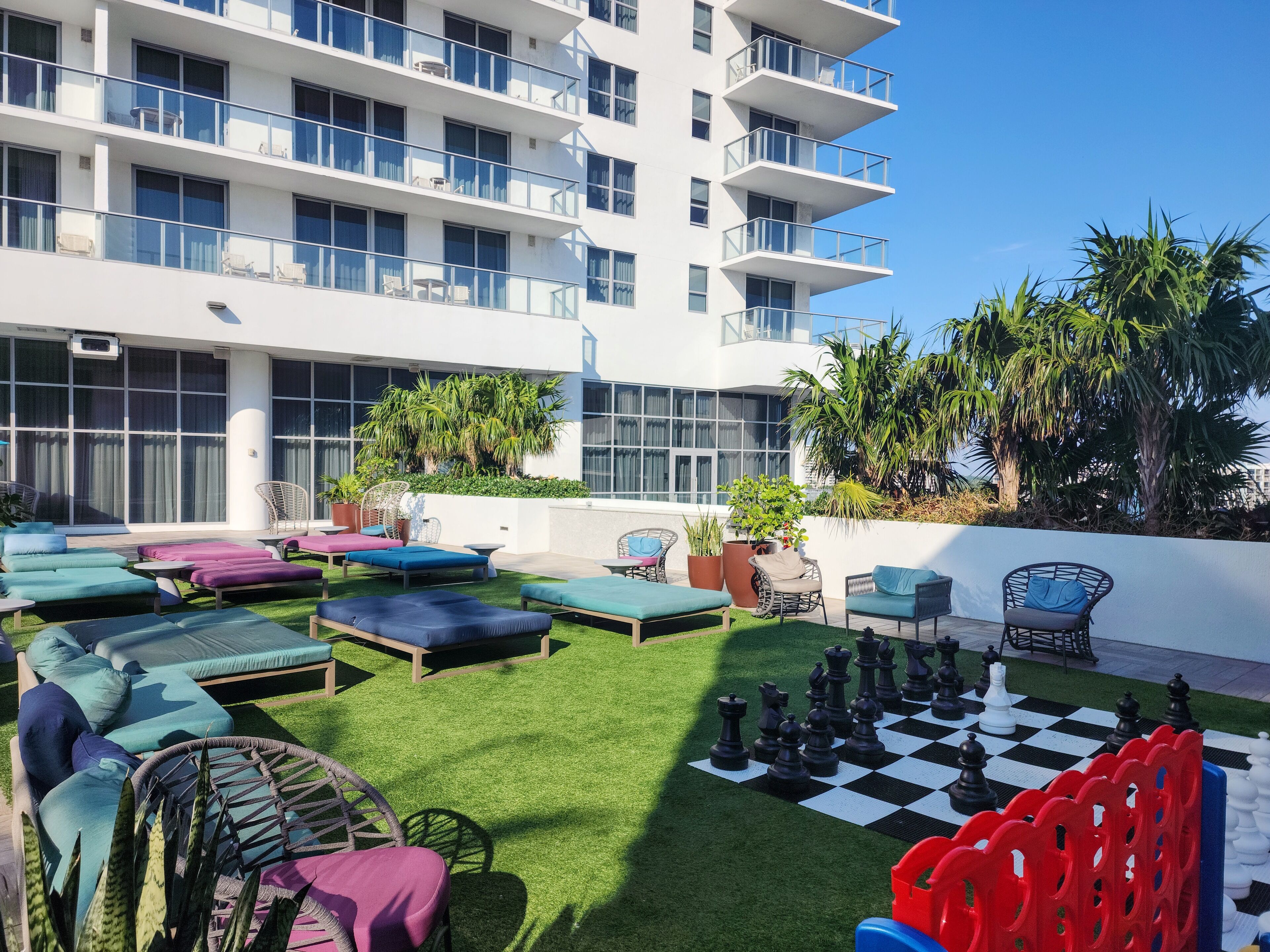 A rooftop patio with outdoor seating, a chessboard, and a view of a modern building.