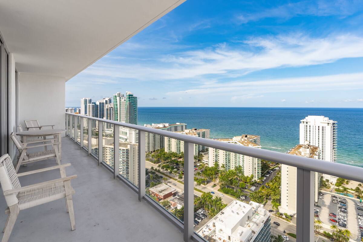 A balcony with a view of the ocean and high-rise buildings.