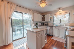 Una cocina moderna con armarios blancos, una isla central y un comedor con vistas.