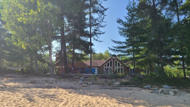 Une maison entourée d’arbres et de sable.
