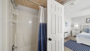 Ein Schlafzimmer mit Bett, Nachttisch, Lampe, Fenster und Tür.