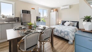Eine kompakte Wohnung mit Küchenzeile, Essbereich, Bett und kleinem Badezimmer.