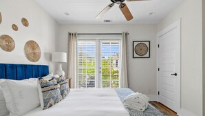 A bedroom with a bed, a ceiling fan, a window with blinds, and a door. - Spring St - Downtown - Walk Everywhere! (Charleston)