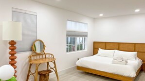 A modern bedroom with a wooden bed, a bedside table with a lamp, a mirror, and two windows with blinds. - SOUTH BEACH, SOFI, Minutes From Beach! (Miami Beach)