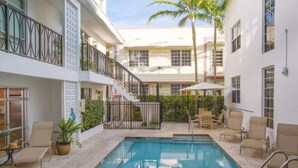 A pool area with a staircase leading to a balcony, surrounded by lounge chairs and a palm tree. - SOUTH BEACH, SOFI, Minutes From Beach! (Miami Beach)