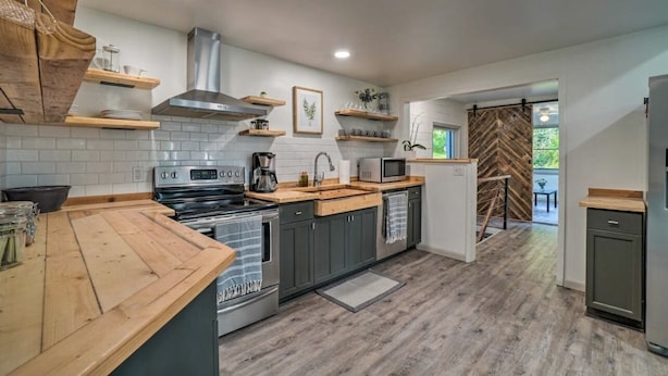 Una cucina moderna con piani in legno, piano cottura integrato e parete con motivo a spina di pesce.