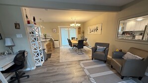 Un salon moderne avec un coin repas, une cuisine à l’arrière-plan et un escalier menant à un autre niveau.