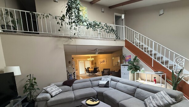 Un salon spacieux comprenant un grand canapé d’angle, une table basse et un escalier menant à l’étage supérieur.
