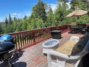 Enjoy al fresco dining on the deck, surrounded by a forested landscape.