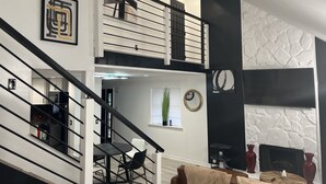 Un salon moderne avec un escalier, une cheminée et un coin repas.