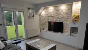 Una sala de estar moderna con una pared de piedra, un televisor de pantalla plana, un sofá gris y una mesa de centro.