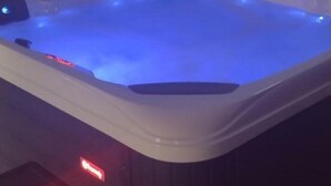 Un jacuzzi con iluminación azul, un banco de madera y una luz roja en el suelo.
