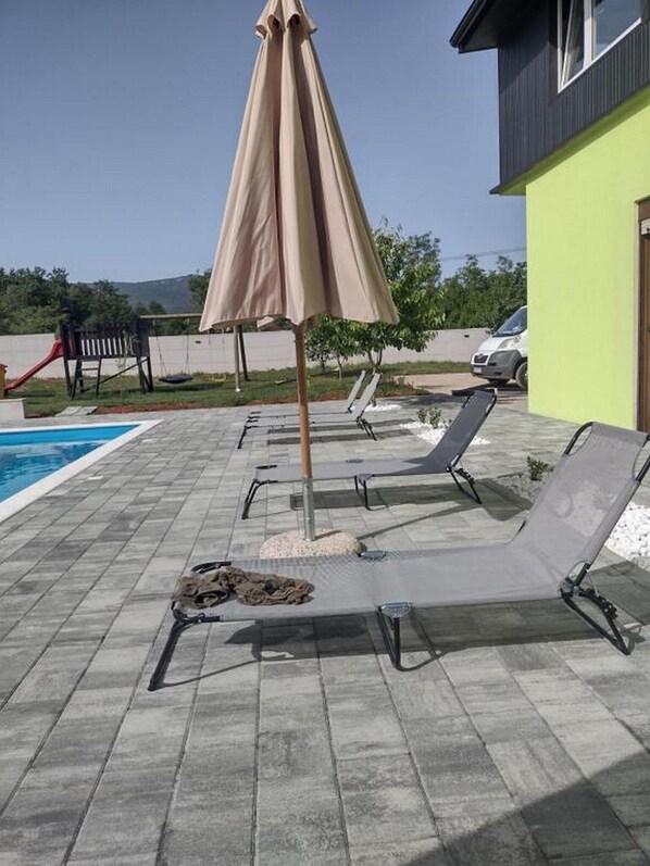 A poolside area with lounge chairs and a covered umbrella.