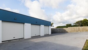 A building with four white garage doors and a blue roof. - Santa Bárbara Sunset 27 C (Santa Bárbara)