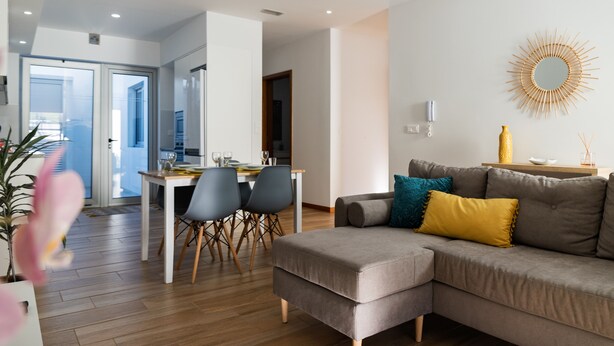 A modern living room with a sofa, a dining table with chairs, and a kitchen in the background. - Santa Bárbara Sunset 27 C (Santa Bárbara)