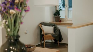 Moderni olohuone, jossa on puinen pöytä, rottinkikori ja maljakko täynnä kukkia.