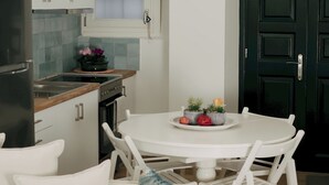 A modern kitchen with white cabinets, a black refrigerator, and a dining area with a white table and chairs.