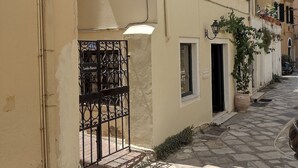 A narrow street with buildings featuring balconies and a gate labeled "Lenko Bianco".