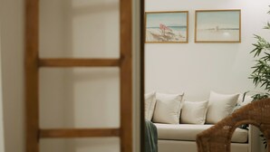 A room with a wooden door, a sofa, two framed pictures on the wall, and a plant.