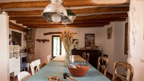A rustic dining room with a long table, wooden chairs, and a blue tablecloth. - Rural house in a small town. (Aler)