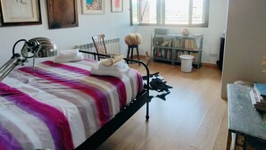 A bedroom with a bed, a desk, a chair, and a window. - Rural house in a small town. (Aler)
