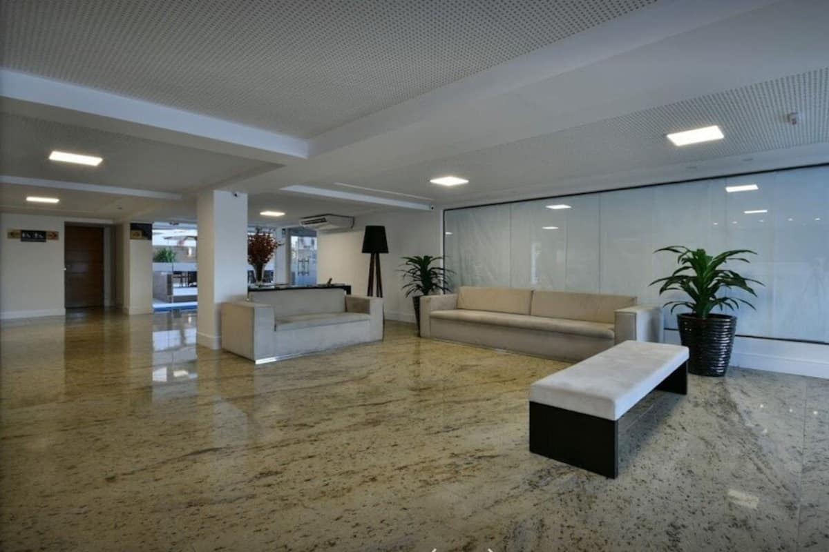En rymlig entréhall med ett marmorgolv, en receptionsdisk, en soffa, en bänk och krukväxter.