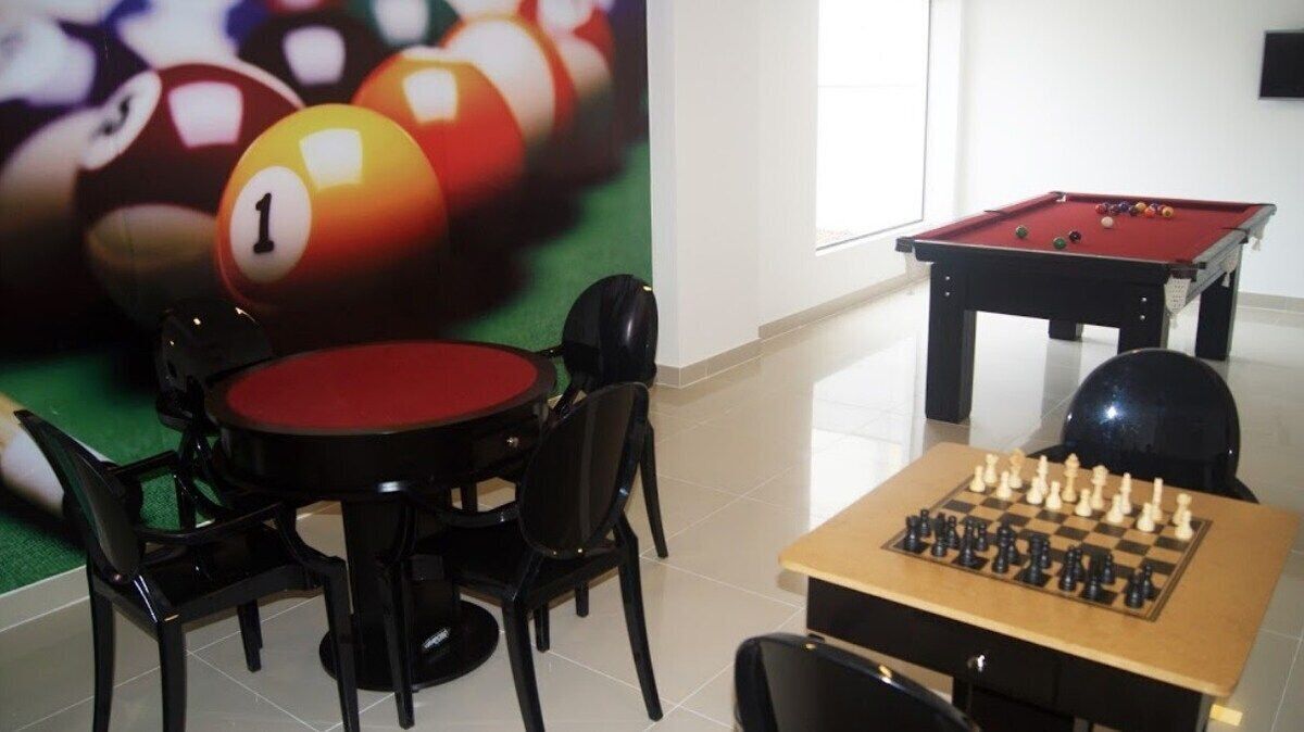 Una mesa de billar, una mesa de pool y una mesa de ajedrez en una habitación con piso de baldosas.