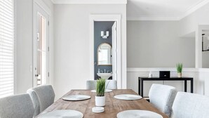 Une salle à manger avec une table en bois, des chaises à revêtement gris et une plante au centre.