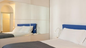 A hotel room with a large mirror reflecting the bed and a nightstand with a lamp. - Appartamento Ariento (Florence)