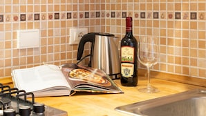 A kitchen counter with a cookbook, a bottle of wine, a wine glass, a kettle, and a sink. - Appartamento Ariento (Florence)