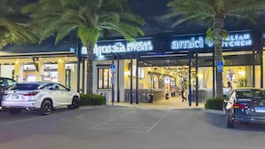Um restaurante chamado 'Amici Italian Kitchen' com mesas ao ar livre e palmeiras.