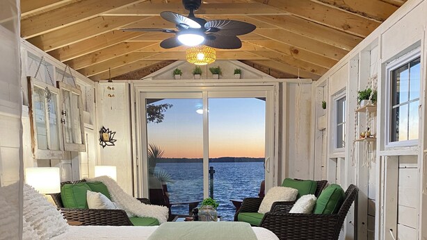 Ein gemütliches Schlafzimmer mit einem großen Bett, zwei Korbstühlen und einem Deckenventilator, mit Blick auf das Meer.