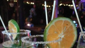 Trois verres d’une boisson verte, garnis de rondelles de citron vert et accompagnés de pailles, sont disposés sur un plateau à motifs.
