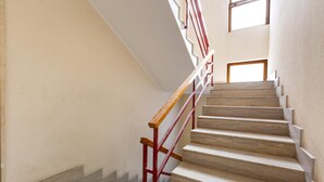 Eine Treppe mit Holzboden und roten Geländern, die zu einer Aussichtsplattform mit einem Fenster führt.