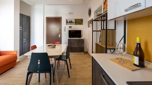 Eine moderne Küche mit Essbereich, einer Couch und einer Weinflasche auf der Arbeitsfläche.
