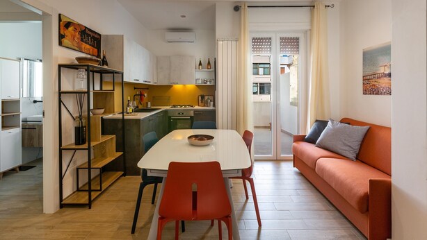 Eine moderne Küche mit Essbereich, einer Couch und einer Treppe, die auf einen Balkon führt.