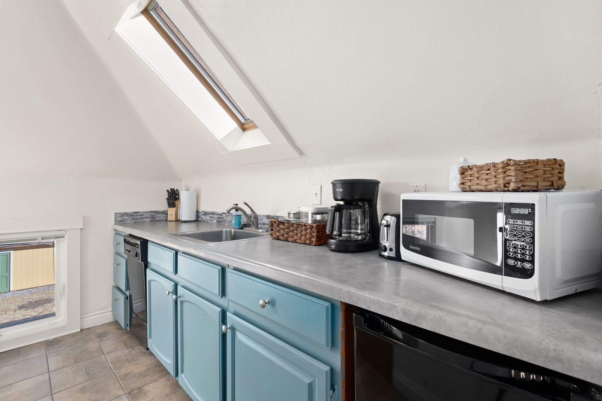 A modern kitchen with a skylight, a coffee maker, a microwave, and a dishwasher.