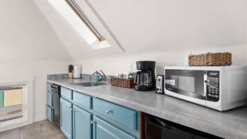 A modern kitchen with a skylight, a coffee maker, a microwave, and a dishwasher.