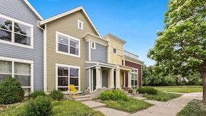 A multi-story residential building with a front porch, a small garden, and a visible yellow chair. - Mid-century Mod Retreat Near Old Town – Free Bikes (Fort Collins)