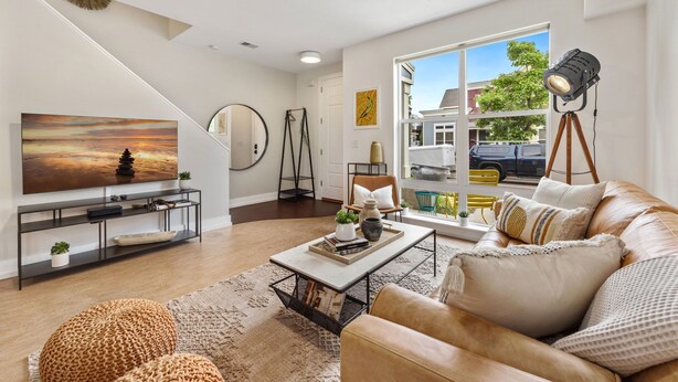 A modern living room with a large TV, leather sofa, and a coffee table with decorative items. - Mid-century Mod Retreat Near Old Town – Free Bikes (Fort Collins)