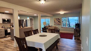 A spacious dining area with a large table and chairs, a kitchen with modern appliances, and a view of the outdoors through large windows. - Cozy Lake and Mountain View House (Somers)