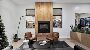 A modern living room with a fireplace, leather sofas, a coffee table, and a Christmas tree.