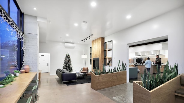 A modern office space with a wooden reception desk, a Christmas tree, and a kitchen area.