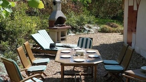 An outdoor patio with a table set for four, surrounded by six striped lounge chairs. - Gîte Les Glycines, Sologne getaway, nature & relaxation 10 min from Chambord (Crouy-sur-Cosson)