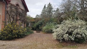 A gravel pathway leading to a building with a brick facade and a red roof. - Gîte Les Glycines, Sologne getaway, nature & relaxation 10 min from Chambord (Crouy-sur-Cosson)
