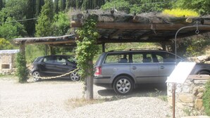 A car parked under a wooden structure with a stone wall and a rope barrier. - Farmhouse with beautiful pool and jacuzzi, panoramic location in chianti (castellina in chianti)