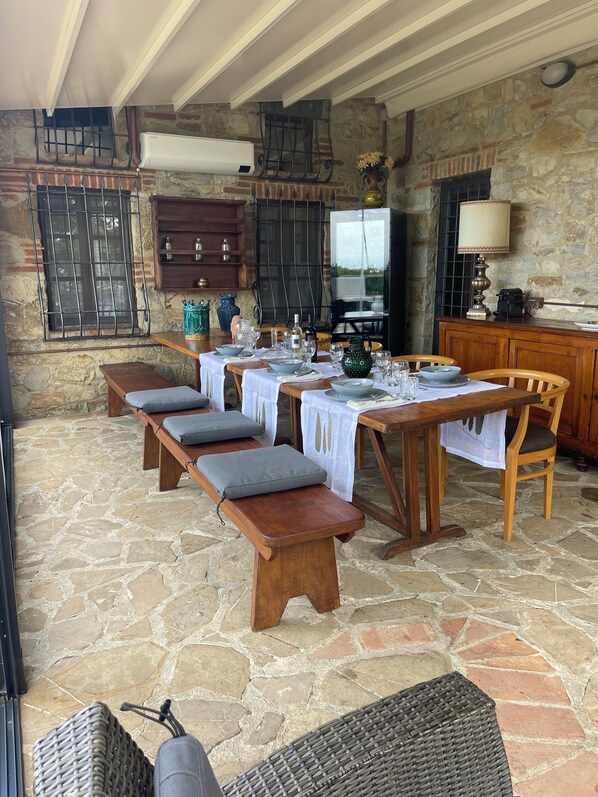 A stone-floored dining area with wooden benches and tables set for a meal. - Farmhouse with a beautiful pool and hot tub, in a scenic location in Chianti (castellina in chianti)
